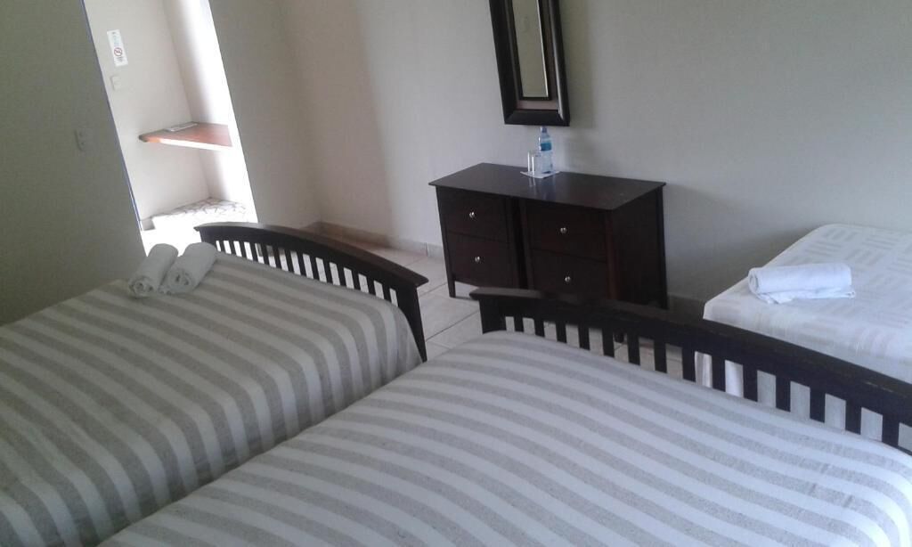 A room with two beds, a dresser, and a mirror.