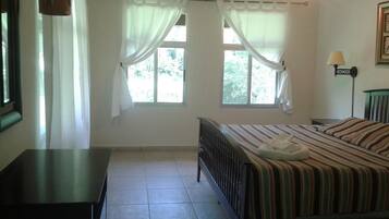 A bedroom with a bed, a nightstand, a lamp, and a window with curtains.