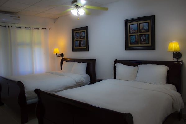 Two single beds with wooden headboards, a ceiling fan, and framed pictures on the walls. - Hotel Campestre (El Valle de Anton)