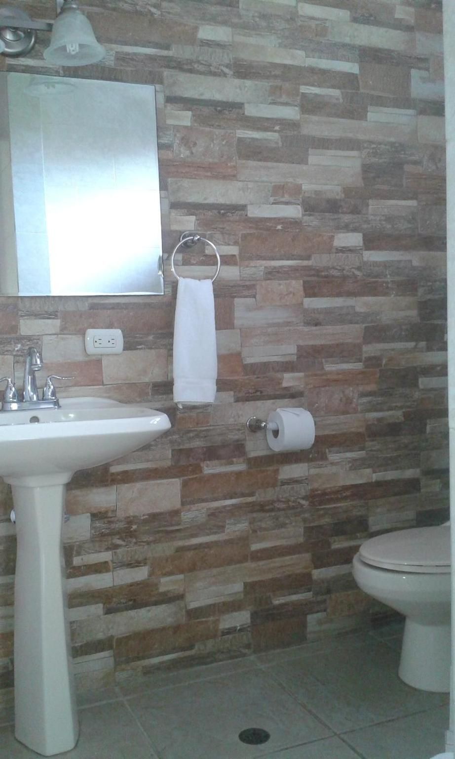 A bathroom with a white sink, a toilet, a mirror, and a towel rack.