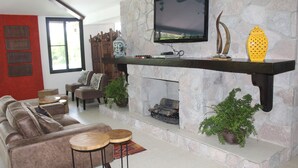 A living room with a stone fireplace, a mounted TV, and a sofa.