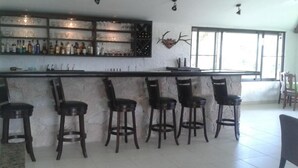 A bar area with a stone countertop, multiple stools, and a wine rack.