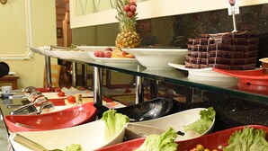 Un bufé con diversas opciones de comida, incluyendo ensaladas, frutas y postres.