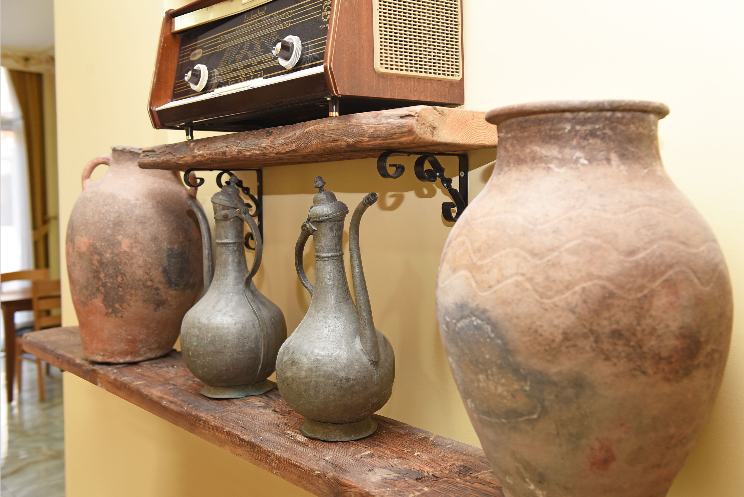 A shelf with three metal vases and a radio.