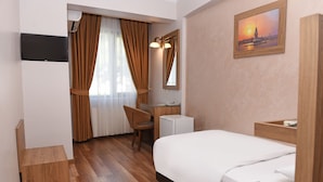 Una habitación de hotel con cama, escritorio, silla, televisor y un cuadro en la pared.