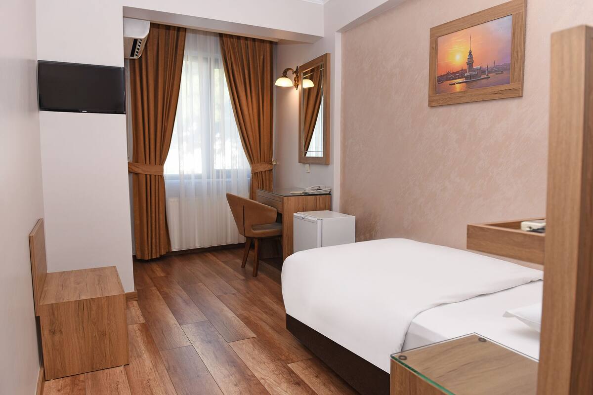 Une chambre d’hôtel avec un lit, un bureau, une chaise, une télévision et un tableau au mur.