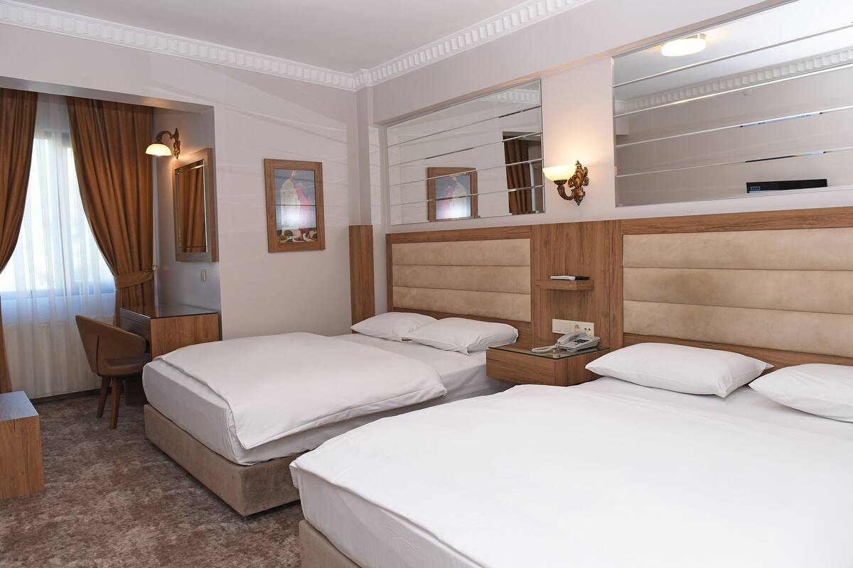 Une chambre d’hôtel avec deux lits, un bureau, une chaise et un grand miroir.
