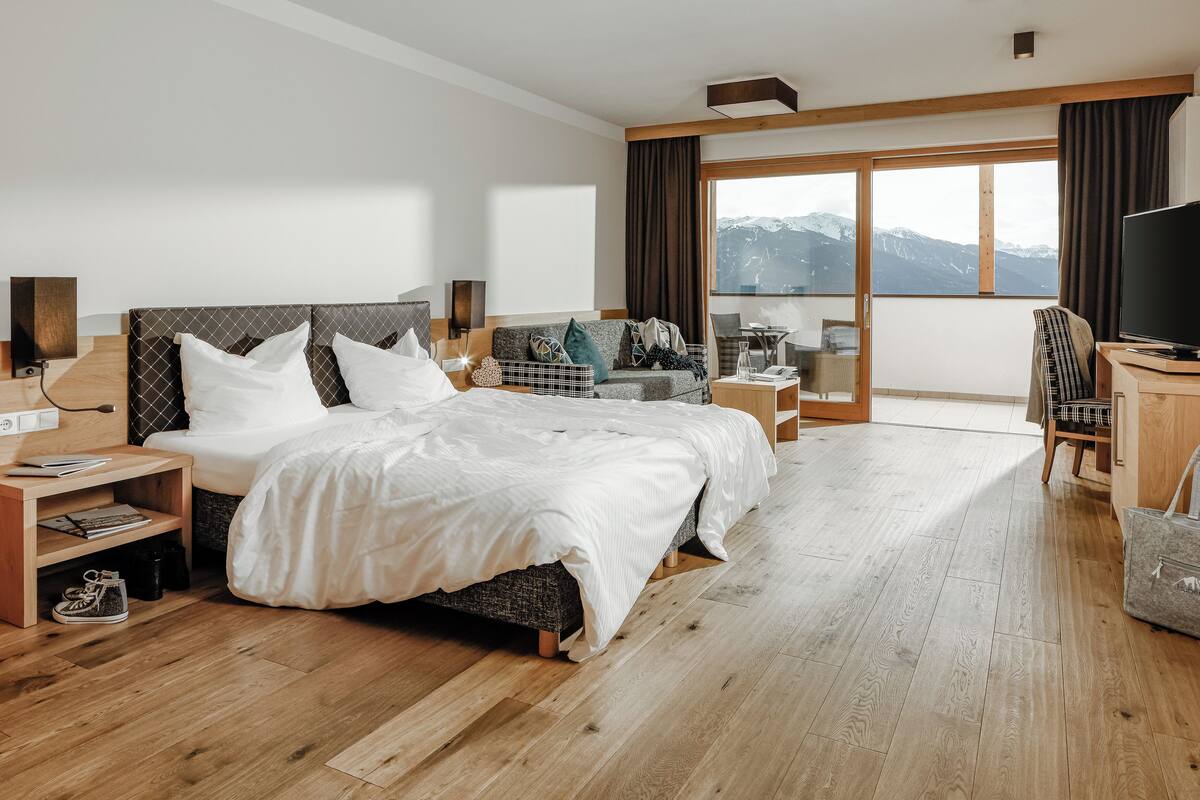 Une chambre d’hôtel avec un grand lit, un canapé, une télévision et une vue sur les montagnes.