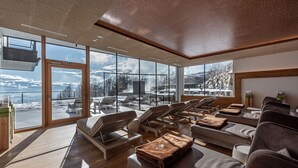 Una stanza luminosa con ampie finestre, pavimento in legno e poltrone da salotto.