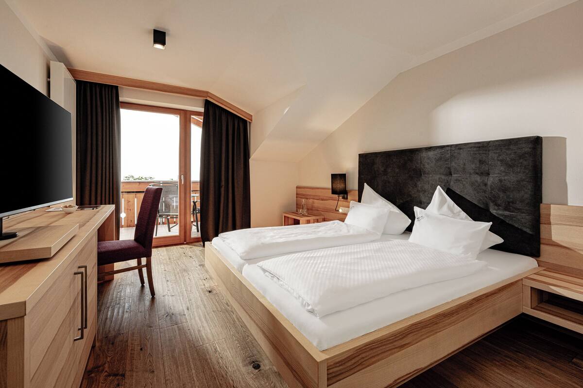 Une chambre d’hôtel moderne avec un lit en bois, un bureau et un téléviseur.