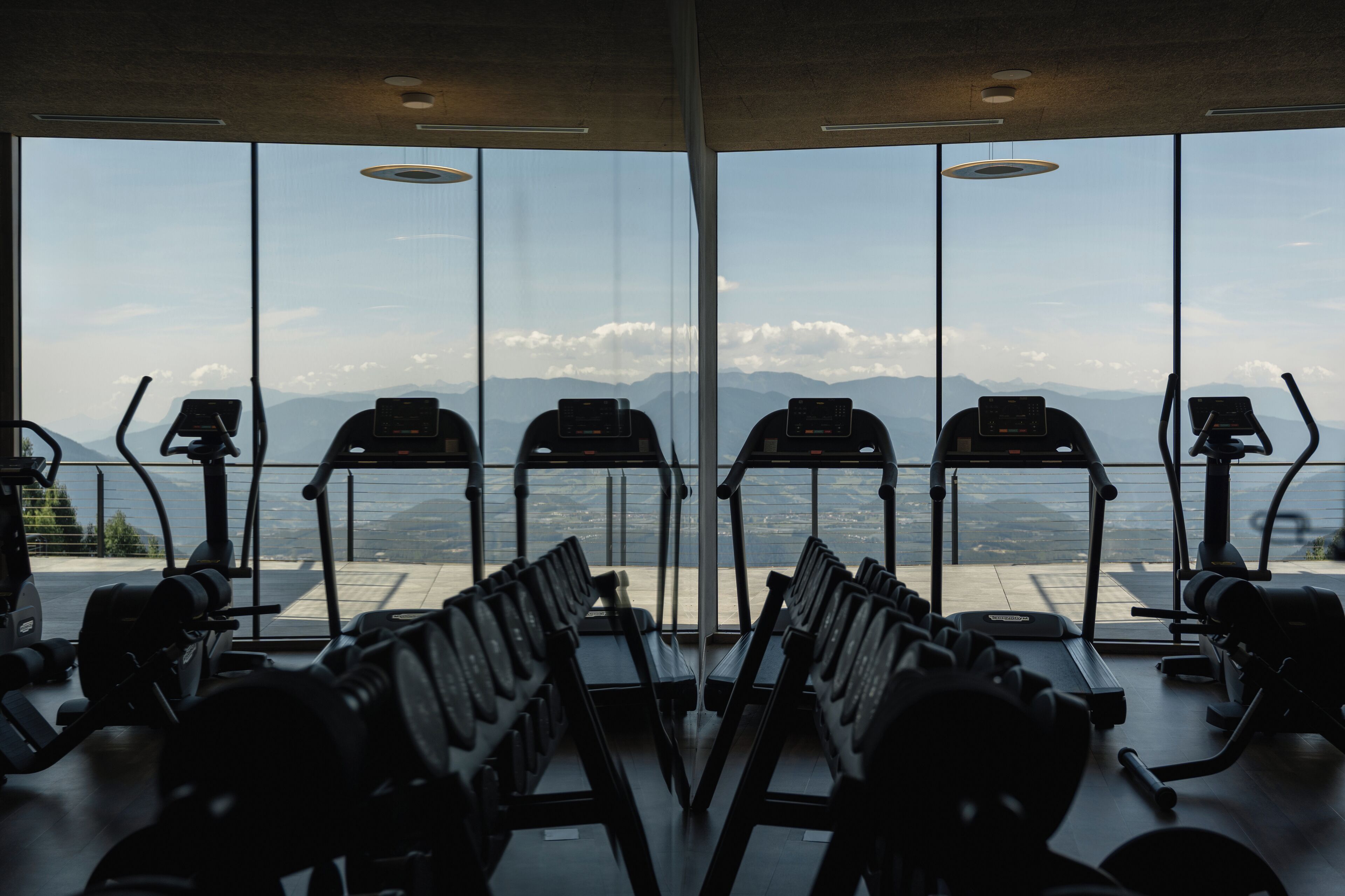 A gym with treadmills and weight machines, large windows with a mountain view.