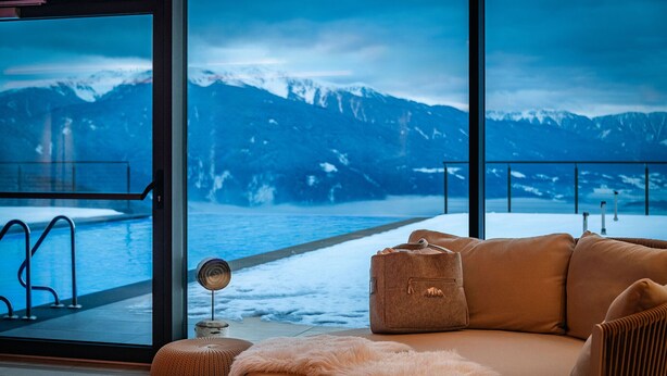 Una camera accogliente con una grande finestra che si affaccia su una montagna innevata e una piscina.