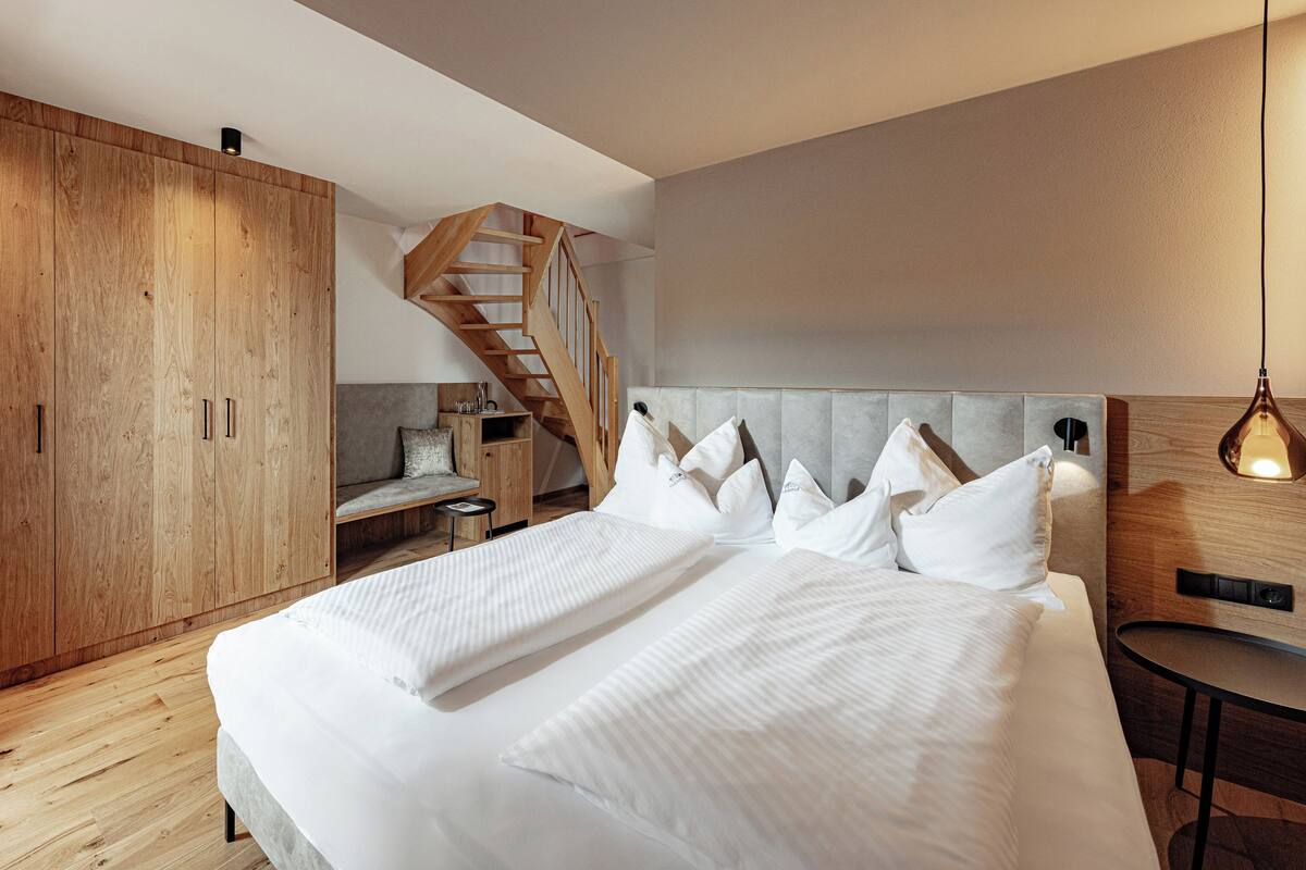 Une chambre moderne avec un grand lit, une armoire en bois et un escalier.
