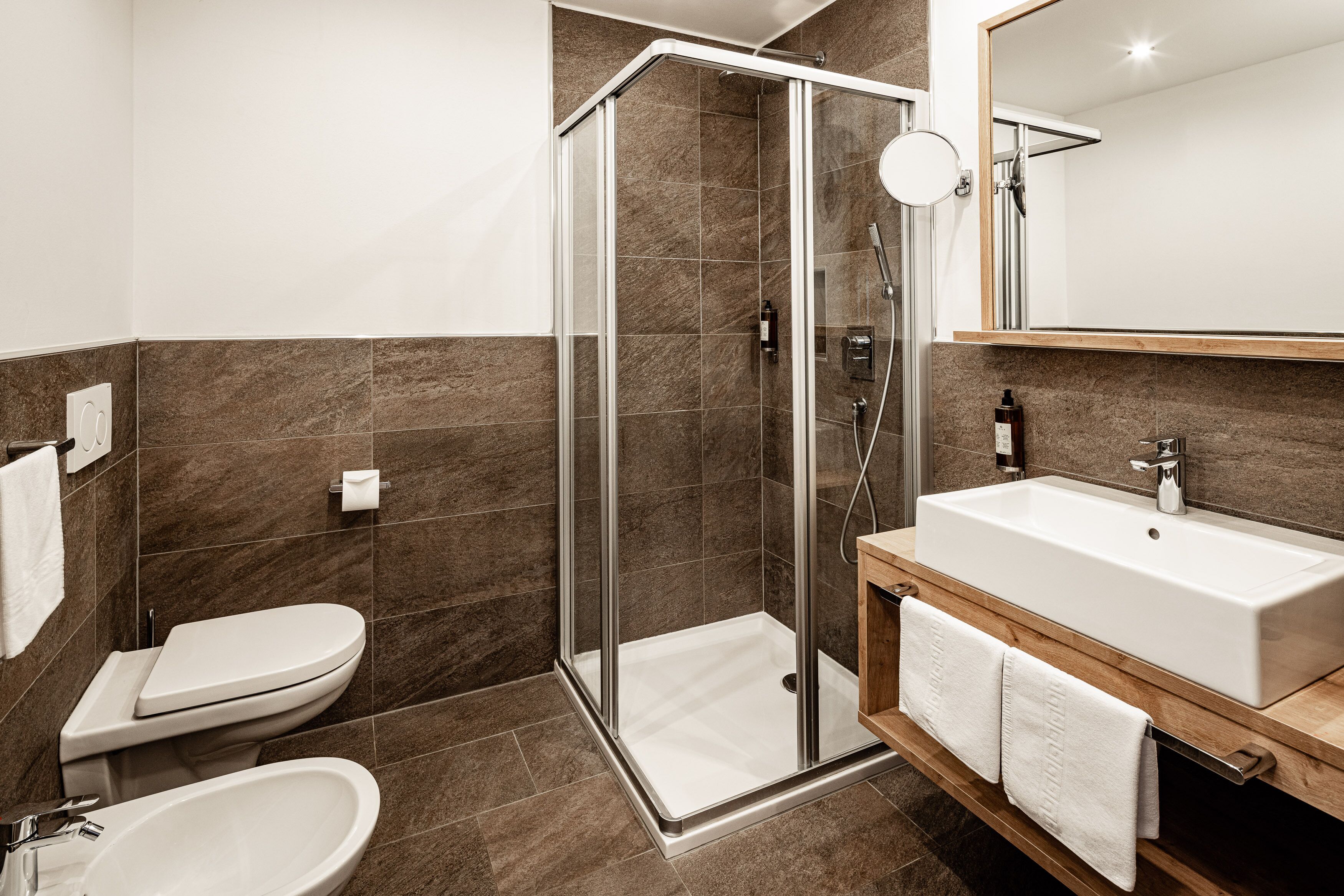 Un baño moderno con ducha de vidrio, lavabo blanco y inodoro.