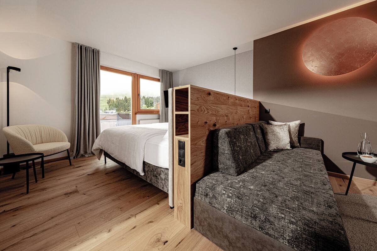 Une chambre d’hôtel moderne, équipée d’un lit, d’un canapé, d’une chaise et d’une petite table.