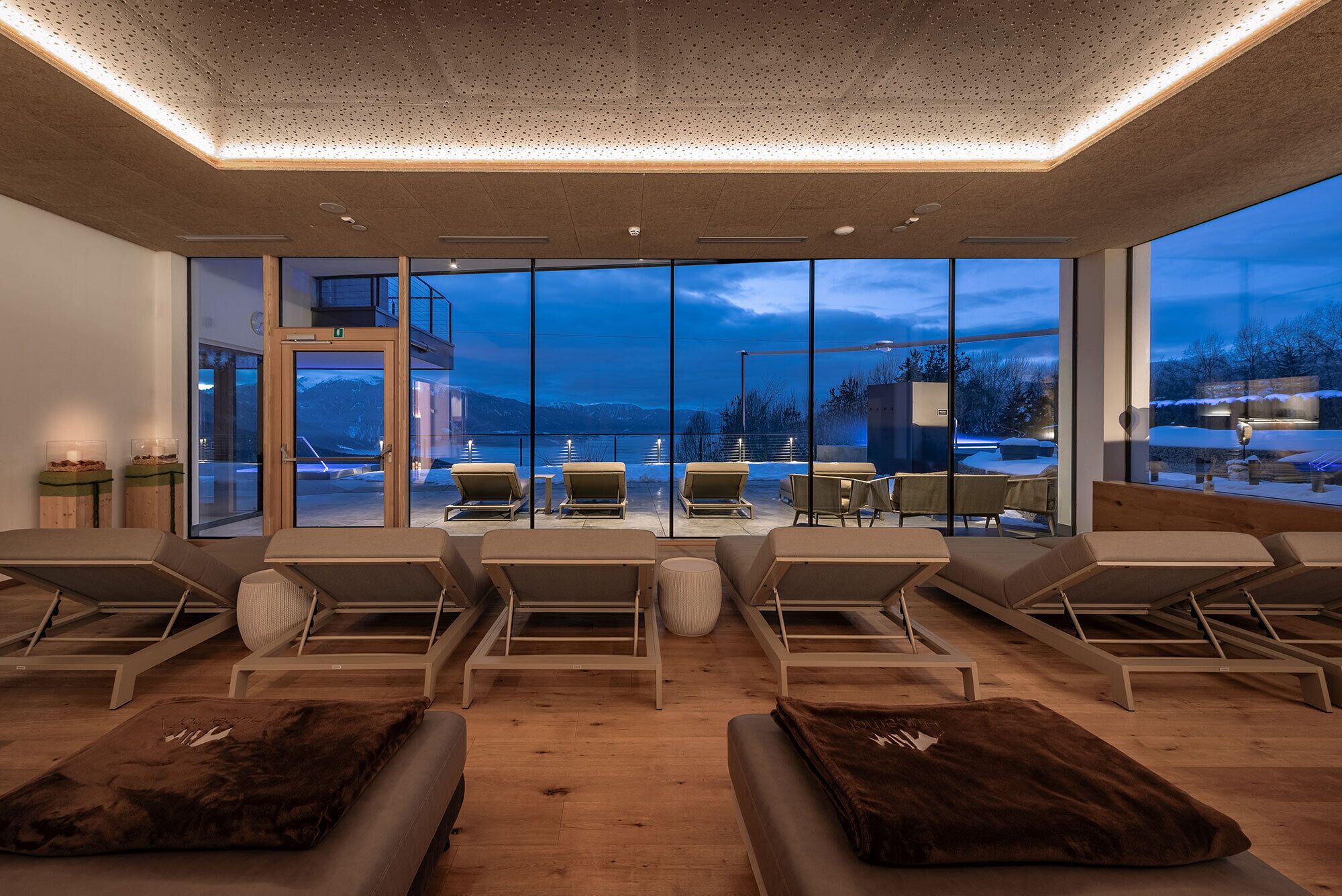 Een spa-ruimte met grote ramen, houten vloeren en meerdere fauteuils.