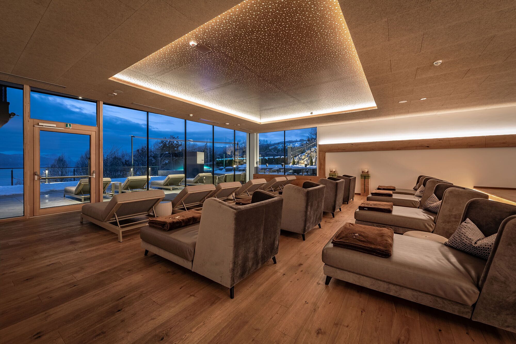 A spacious lounge with multiple seating areas, large windows offering scenic views, and a modern ceiling design.