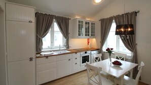 Una cocina con muebles blancos, encimera de madera, un fregadero, un horno y una mesa de comedor con sillas.