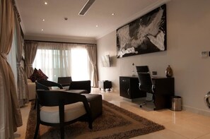 A modern living room with a sofa, chairs, a desk, and a large abstract painting on the wall. - L'eola Suites (Abuja)