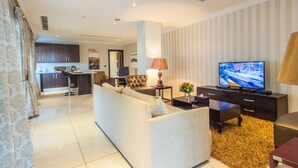 A modern living room with a sofa, TV, and a small table with a lamp. - L'eola Suites (Abuja)