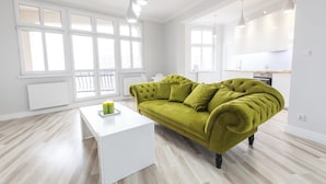 A modern living room with a green sofa, a white coffee table, and large windows. - Homewell Apartments Stara Piekarnia (Poznan)