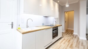 A modern kitchen with white cabinets, a wooden countertop, a built-in oven, and pendant lighting. - Homewell Apartments Stara Piekarnia (Poznan)