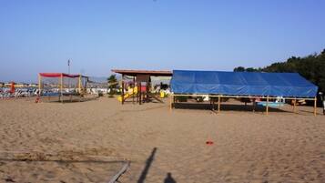 Een privéstrand, ligstoelen aan het strand, parasols, beachvolleybal