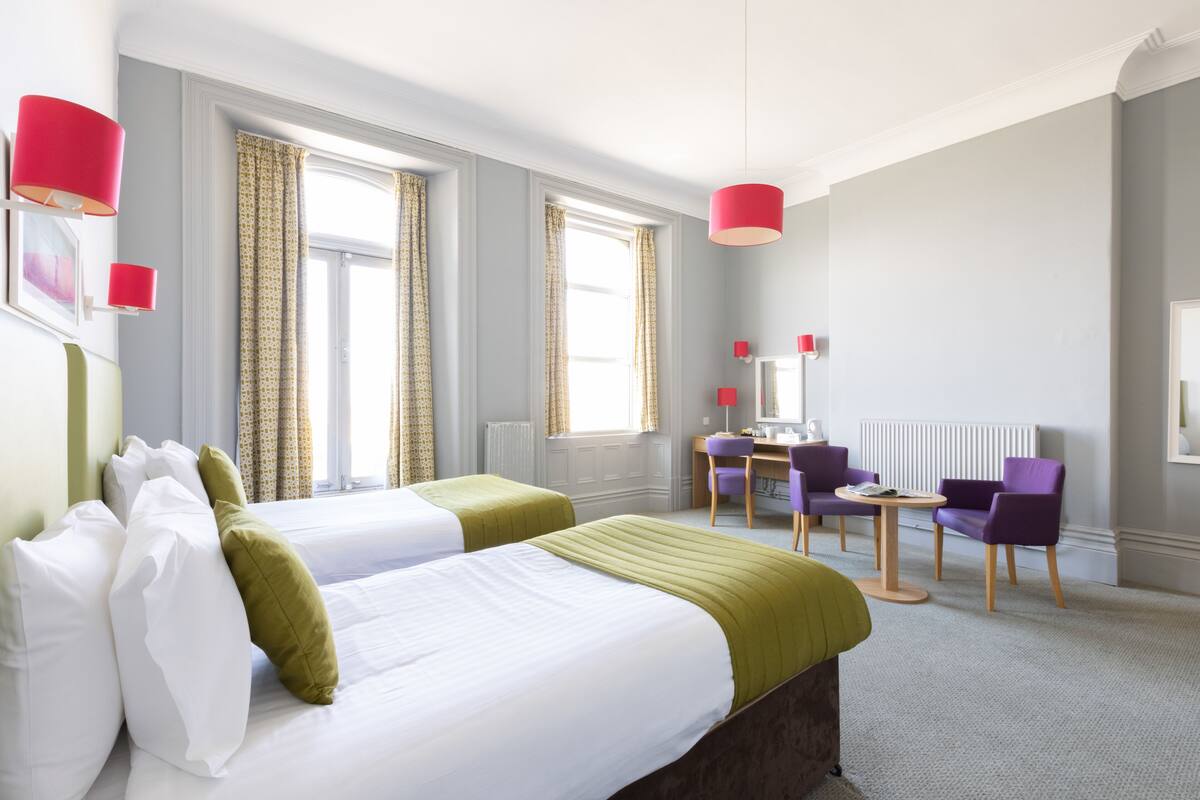 Habitació d'hotel amb dos llits, un escriptori i una cadira.
