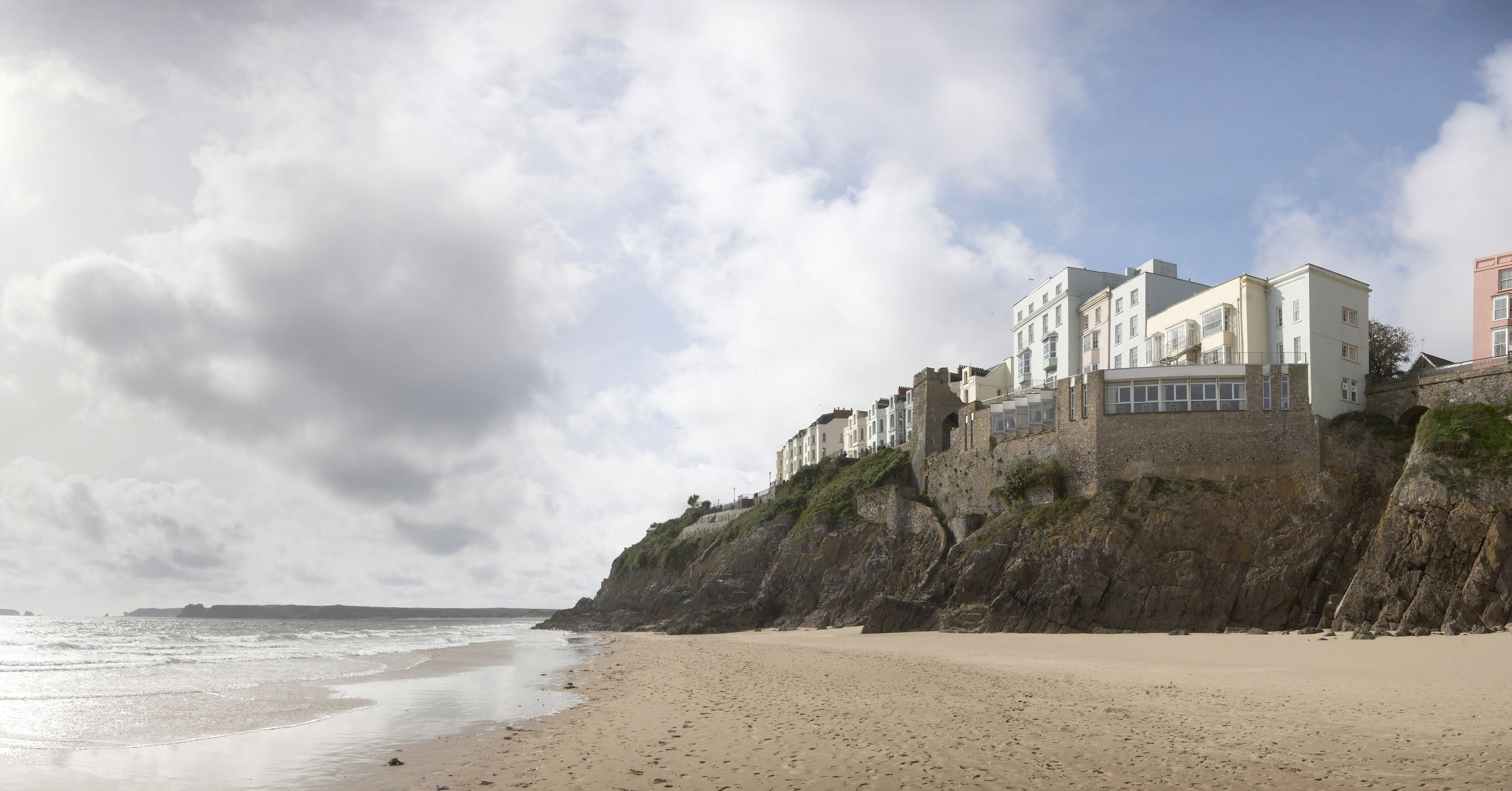 A coastal hotel with a beach view, situated on a cliff overlooking the sea.