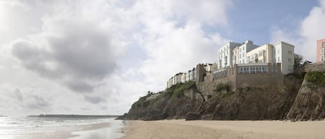A coastal hotel with a beach view, situated on a cliff overlooking the sea.