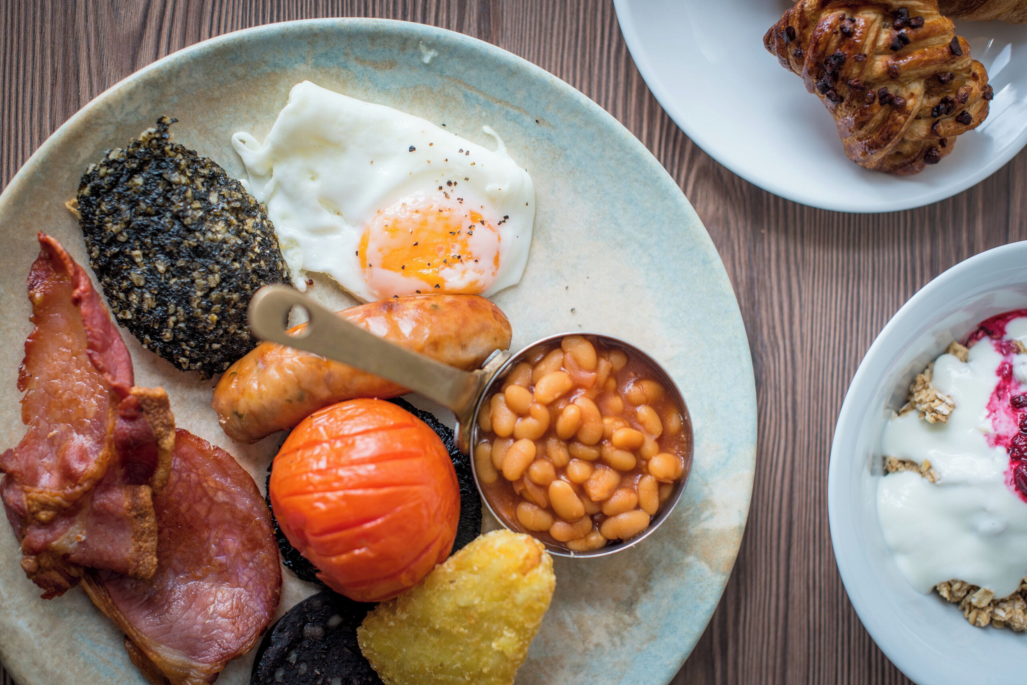 A plate with various breakfast items including eggs, bacon, beans, and a tomato.