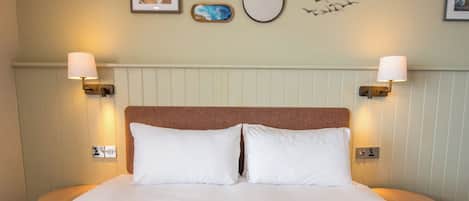 A neatly made bed with white linens and two bedside lamps.