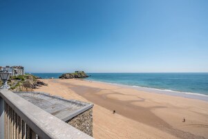 A beach with a clear sky, a sandy shore, and a stone wall in the foreground.