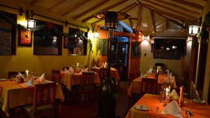 En restaurant med flere borde dækket til spisning, træstole og en hyggelig atmosfære.
