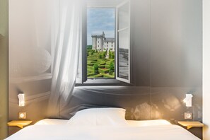 Un dormitorio con un ventanal que ofrece vistas a un castillo y un jardín cuidado.