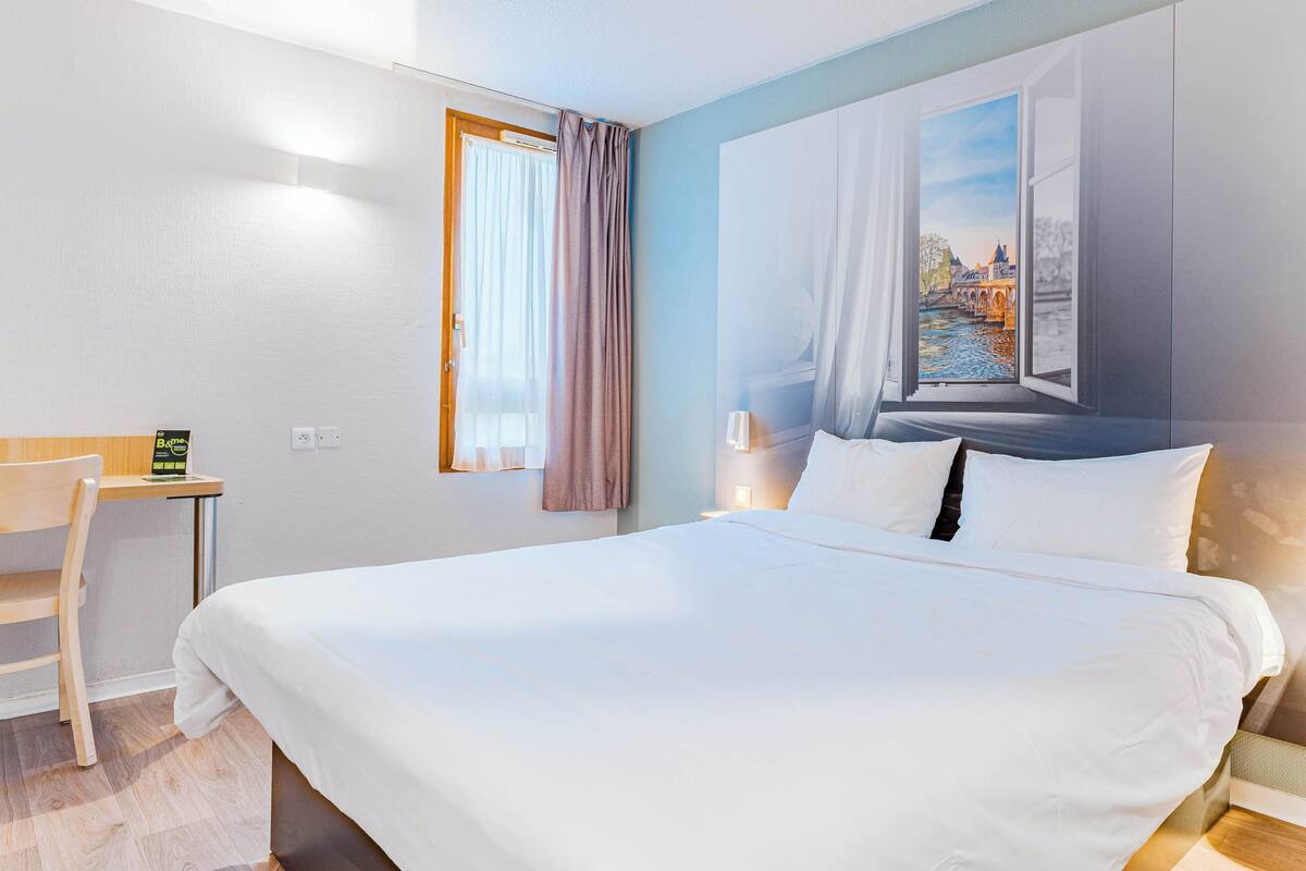 Habitación de hotel con una cama grande, un escritorio y una ventana con vistas a un puente.