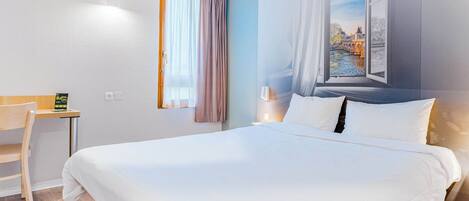 A hotel room with a large bed, a desk, and a window with a view of a bridge.