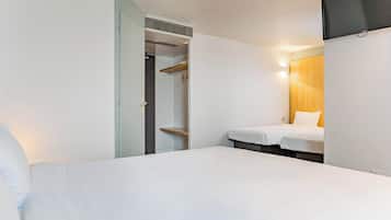 A hotel room with a bed, a bedside table, a wardrobe, and a wall-mounted TV.
