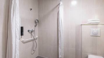 Een moderne badkamer met een inloopdouche, handgrepen, een toilet en een handdoekrek.
