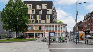 A hotel with a modern facade, a visible entrance, and a bike parking area.
