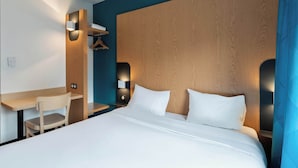 A hotel room with a wooden headboard, a desk, and a chair. - B&B HOTEL Lille Roubaix Campus Gare (Roubaix)