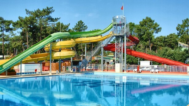 A swimming pool with multiple slides and a small tower structure. - Boost Locamobil 17 Bonne Anse Plage (Les Mathes)