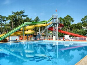A swimming pool with multiple slides and a small tower structure. - Boost Locamobil 17 Bonne Anse Plage (Les Mathes)