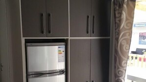 A compact kitchen with a built-in refrigerator and cabinets. - Boost Locamobil 17 Bonne Anse Plage (Les Mathes)