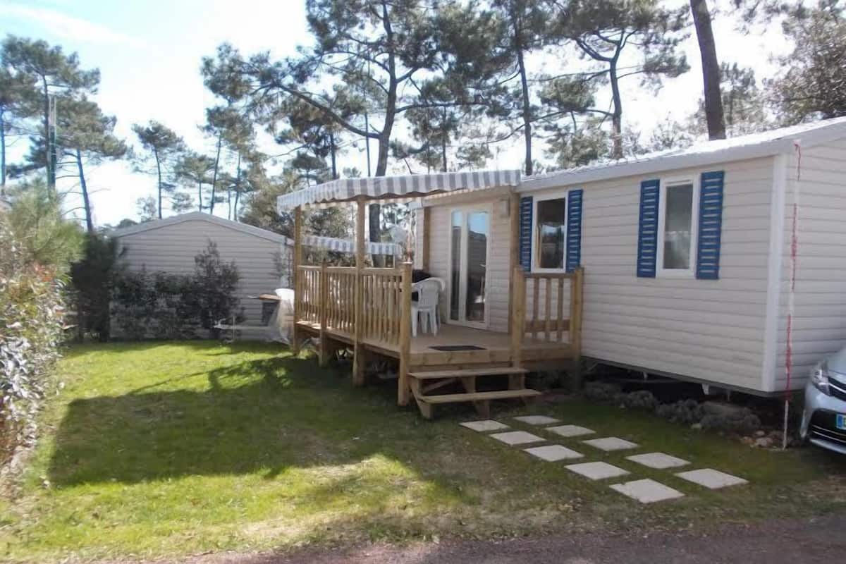 Une maison mobile dotée d’une terrasse, d’un petit jardin et d’une allée pavée.