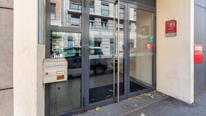 A hotel entrance with a glass door, a fire alarm, and a mailbox. - B&B HOTEL Lyon Caluire Cité Internationale (Caluire-et-Cuire)