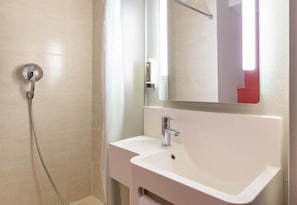 Une salle de bain avec une douche, un lavabo et un miroir.