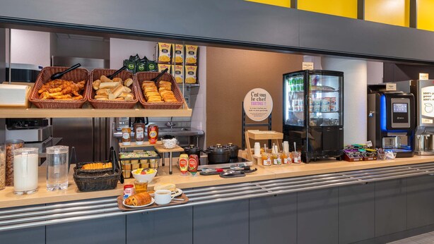 A breakfast buffet with various food items, condiments, and a coffee station. - B&B HOTEL Lyon Caluire Cité Internationale (Caluire-et-Cuire)