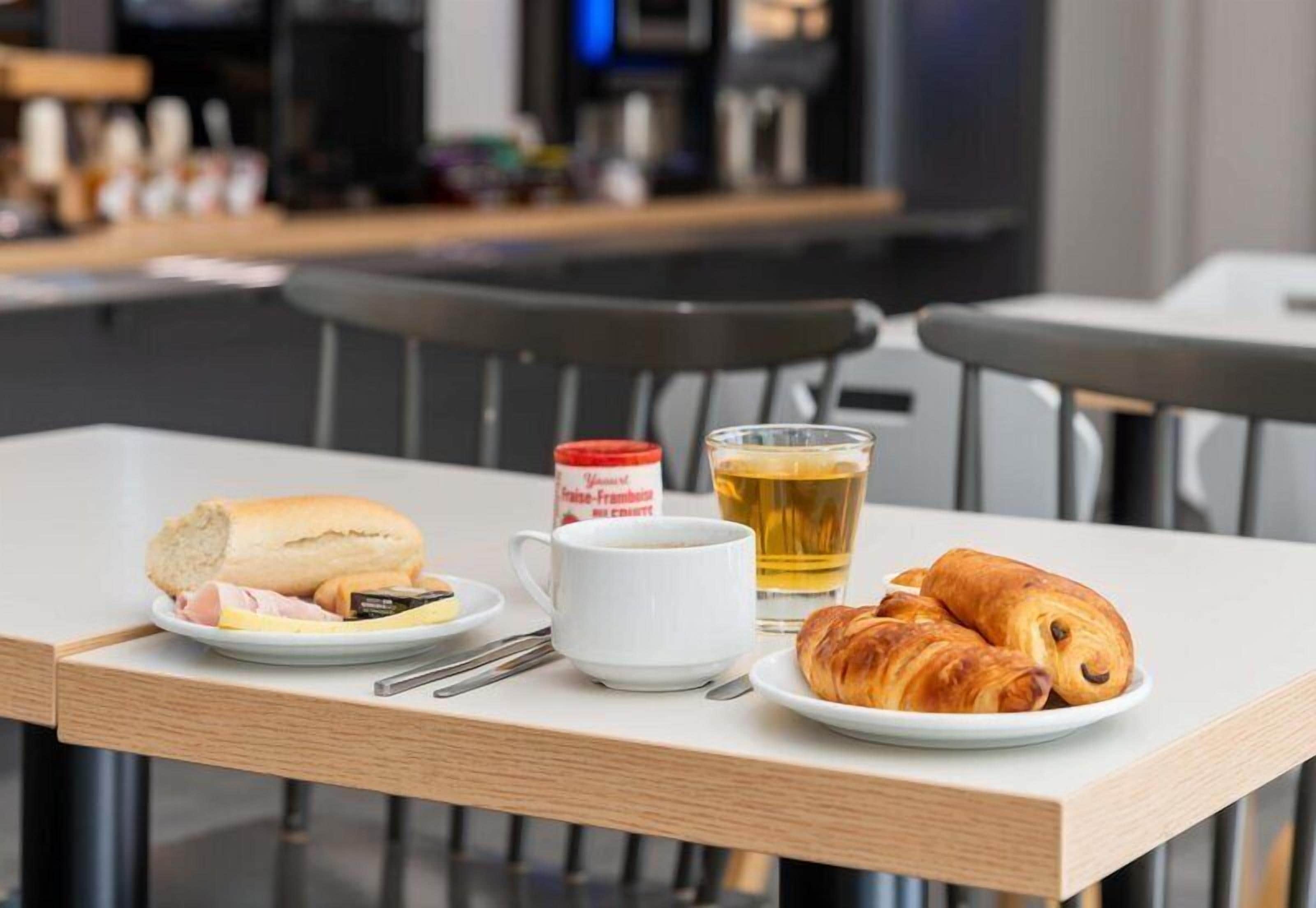 A table with croissants, a plate with ham and cheese, a cup of coffee, and a glass of tea.
