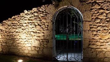 Un mur de pierre avec une porte en métal et un feu vert au-dessus.
